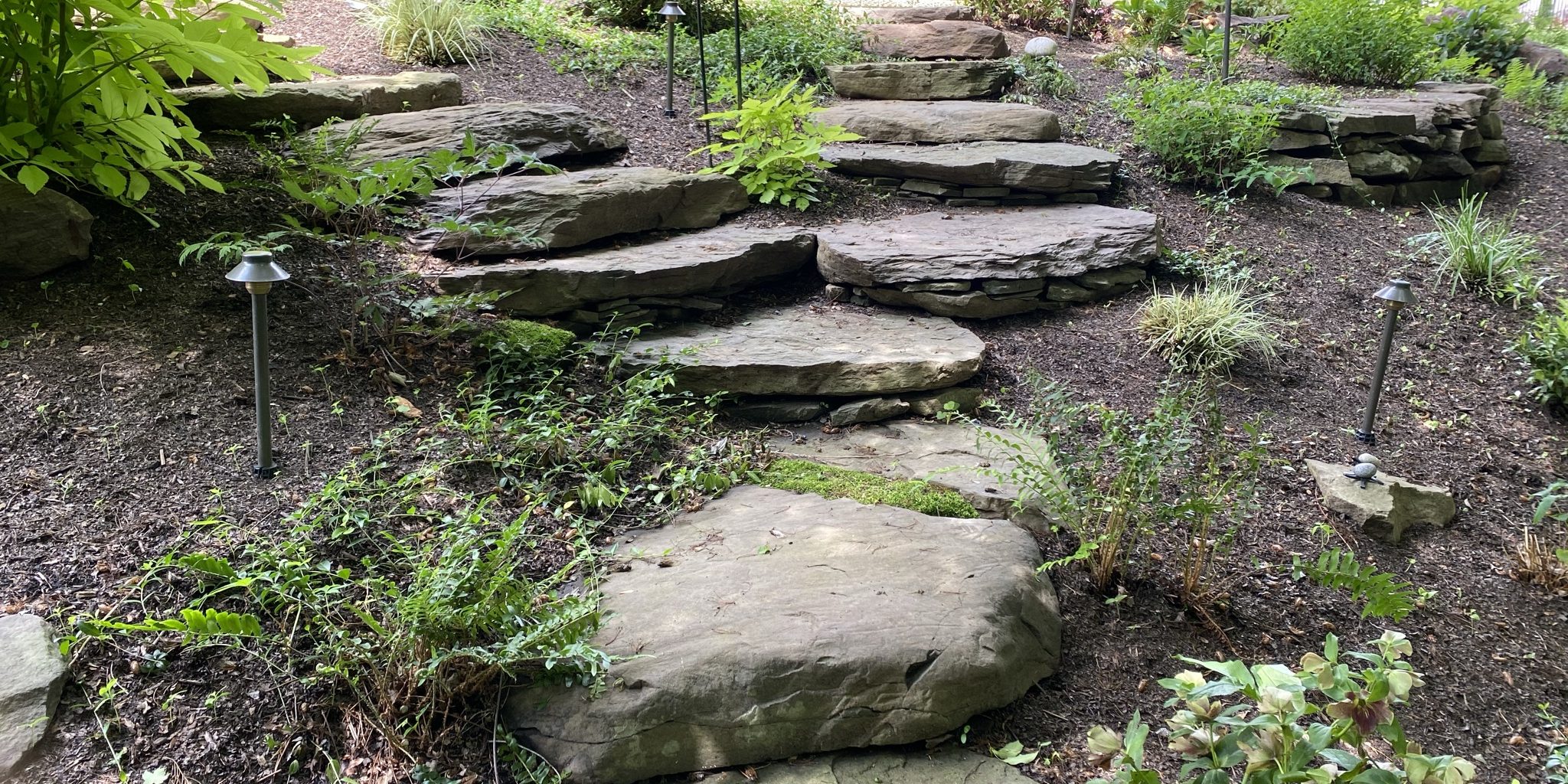 Stone slabs arranged as a staircase on a mulched yard