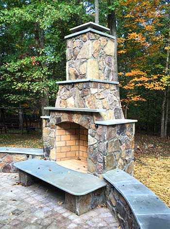 outdoor stone fireplace, hearth and low wall surrounding a stone patio